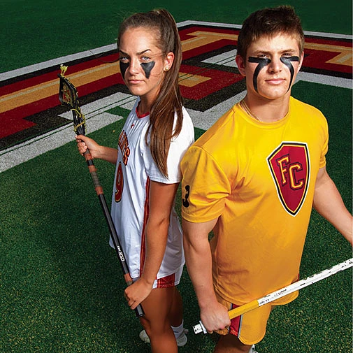 Two lacrosse players standing on a field staring into camera